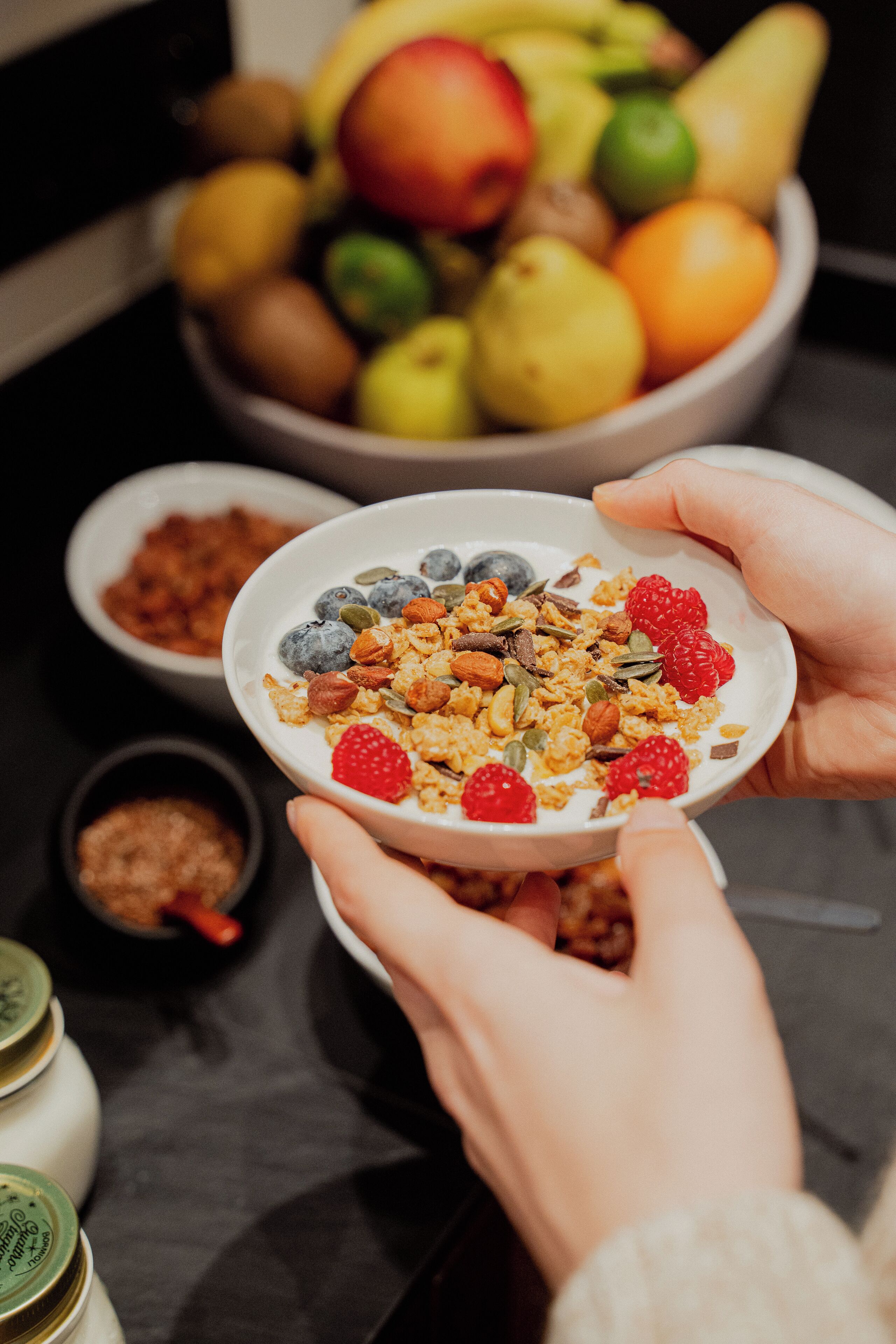 Una ciotola di cereali con frutta e noci, tenuta tra le mani.