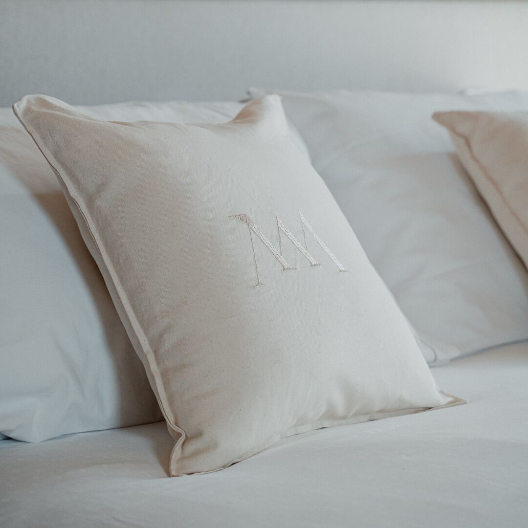 A bed with two pillows, one with a monogram.