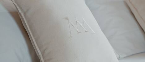 Una cama con dos almohadas, una con un monograma.