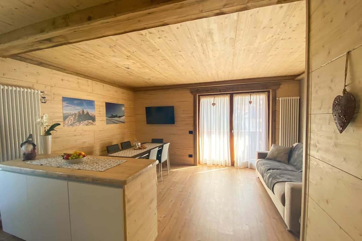 Et træinteriør med et spiseområde, en sofa og en køkkenø.