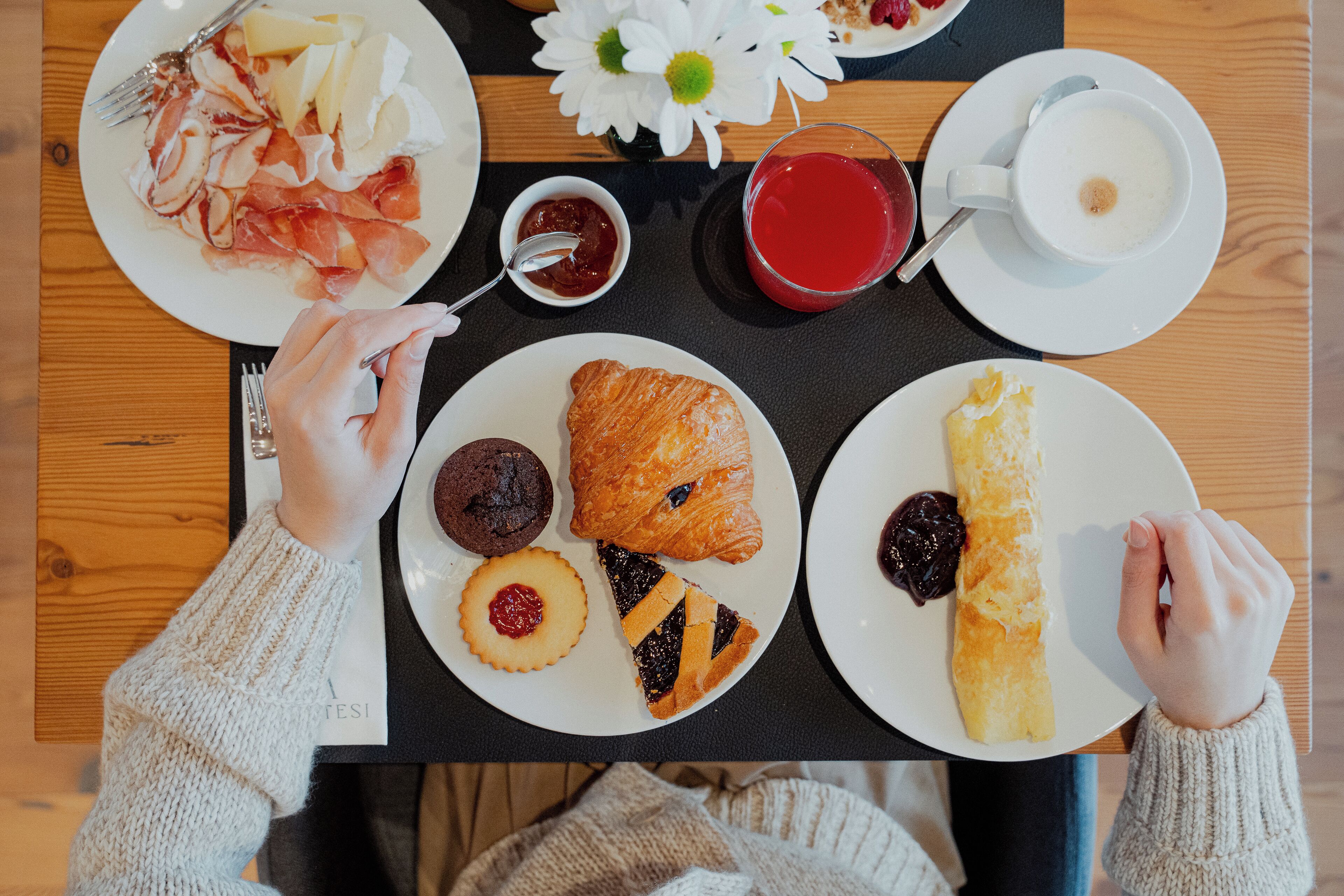 Ein Frühstückstisch mit Speisen, einer Kaffeetasse und einer Blume.
