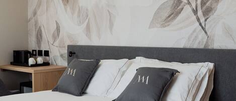 Una camera da letto moderna con un letto grande, due comodini e un mobiletto, e una parete con motivo a foglia.