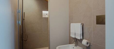 Une salle de bain moderne équipée d’une douche, de deux toilettes et d’un lavabo.