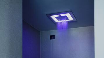A modern shower with a square ceiling light and a visible control panel.