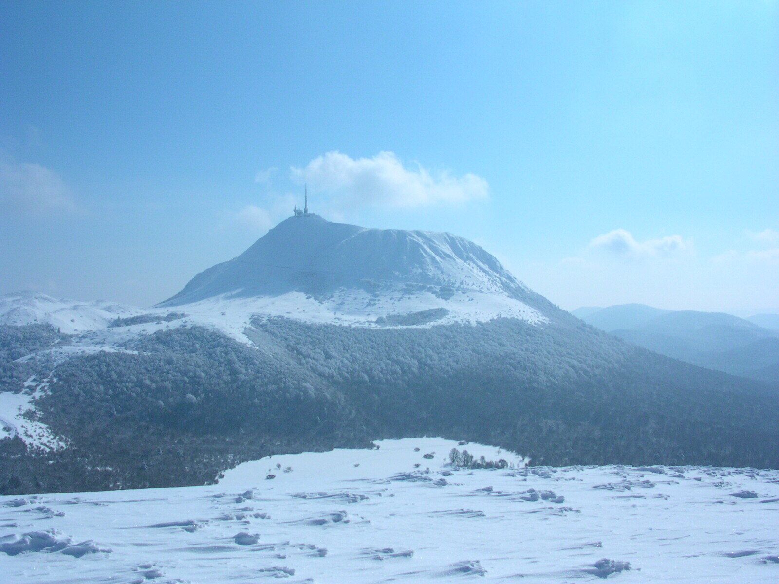 Ein schneebedeckter Berg unter blauem Himmel.