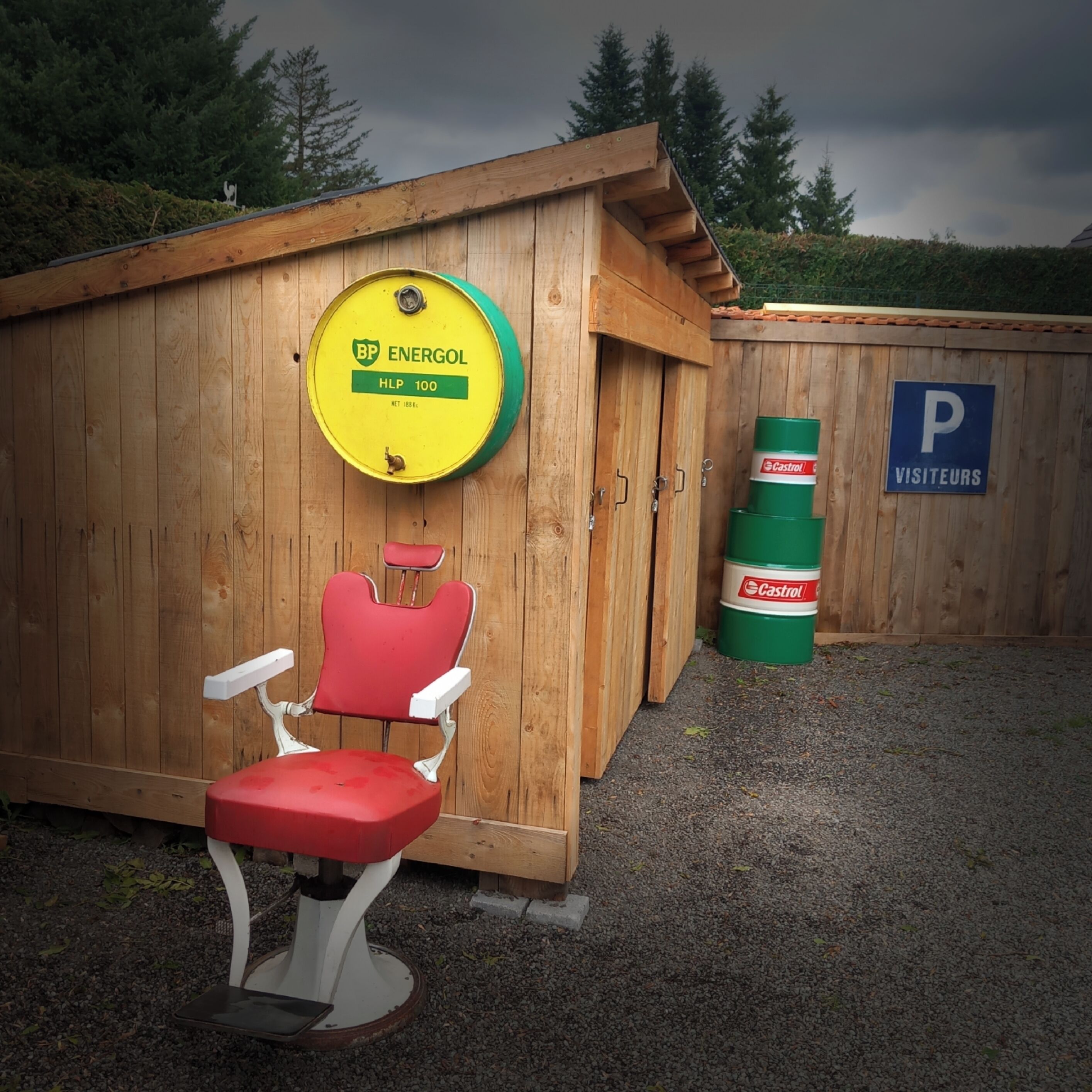 A wooden cabin with a BP Energol fuel canister, a Castrol oil can, and a red chair.