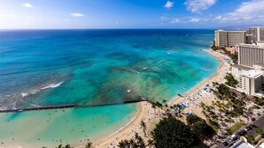 Ein Küstenhotel mit Blick auf den Strand, einen Steg und ein klares, blaues Meer.