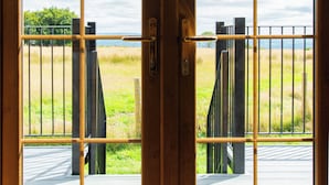 A wooden door with a metal gate, leading to an outdoor area with a grassy field and a clear sky. - Head For The Hills Glamping Shepherd’s Hut. Pet friendly, mountain views

 (Llanfynydd)