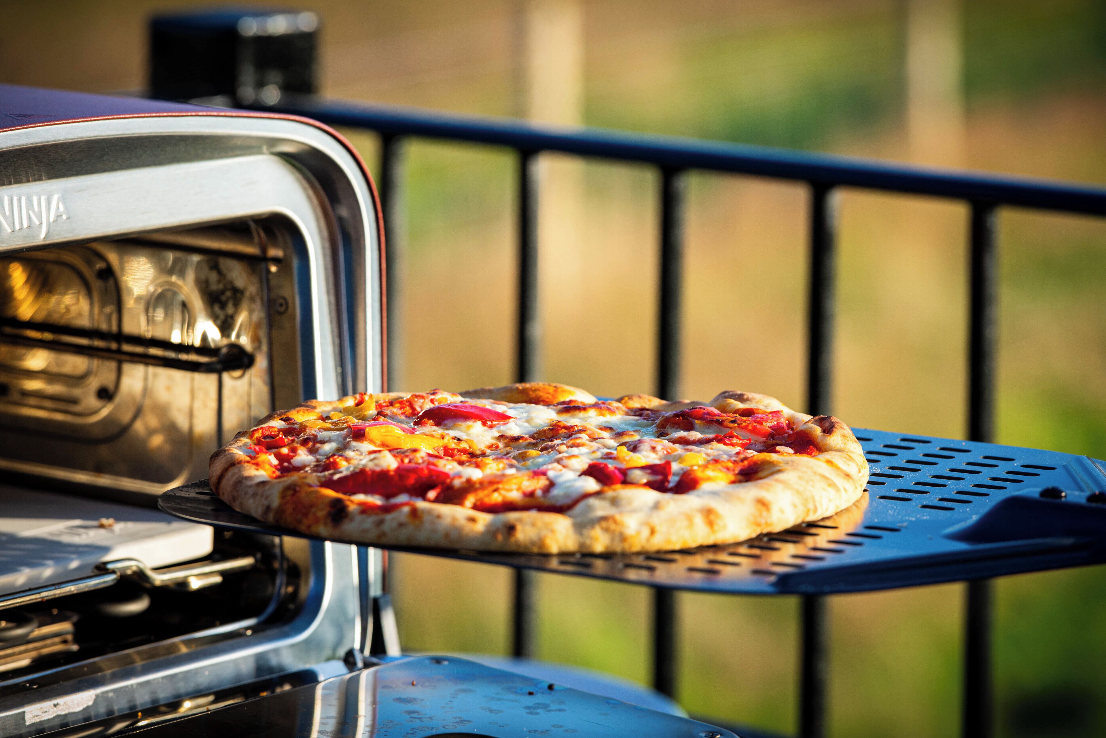 En pizza på ett metallbricka ovanför en grill.