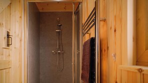 Un intérieur en bois avec un espace douche, comprenant une porte en verre et un porte-serviettes.