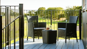 A balcony with two wicker chairs and a small table, a burger on the table, and a view of a grassy area. - Head For The Hills Glamping Shepherd’s Hut. Pet friendly, mountain views

 (Llanfynydd)