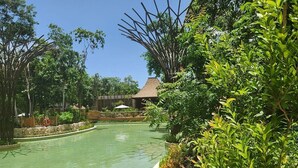 A swimming pool surrounded by lush greenery and a thatched-roof structure. - 2 Bedroom Estates 5 Diamonds, VIP Golf Tournament, VIP Park Access Vidanta World (Nuevo Vallarta)