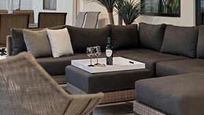 A modern living room with a dark grey sectional sofa, a white coffee table, and a wicker chair. - Bella Palma: Elegance & Style w/Putt, Pool & Spa! (Scottsdale)