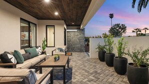 An outdoor patio with a sofa, coffee table, and potted plants. - Bella Palma: Elegance & Style w/Putt, Pool & Spa! (Scottsdale)