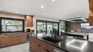 A modern kitchen with wooden cabinets, a black countertop, and a built-in dishwasher. - Bella Palma: Elegance & Style w/Putt, Pool & Spa! (Scottsdale)