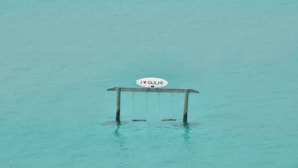 Un columpio sobre aguas turquesas con un cartel que dice "I ♥ GULHII".