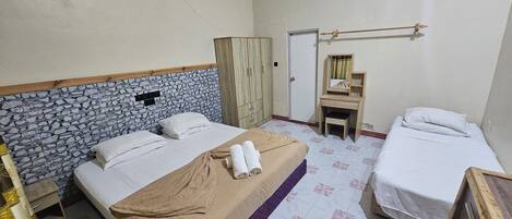 A hotel room with two beds, a wardrobe, a vanity with a mirror, and a ceiling fan.