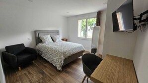 A bedroom with a bed, a chair, a desk, and a TV mounted on the wall. - 3-bedroom house for 4 people (Aix-en-Provence)