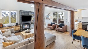 A spacious living area with a fireplace, leather sofas, a dining table, and a kitchen in the background. - Ski-In/Ski-Out via Pony Express Lift (Big Sky)