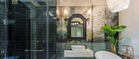 A bathroom with a glass shower enclosure, a white sink, a large mirror, and a freestanding bathtub.