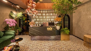 A modern lobby with a geometric patterned floor, a reception desk, green sofas, and various plants. - Ngan Le Mot Dem Hotel (Ho Chi Minh City)