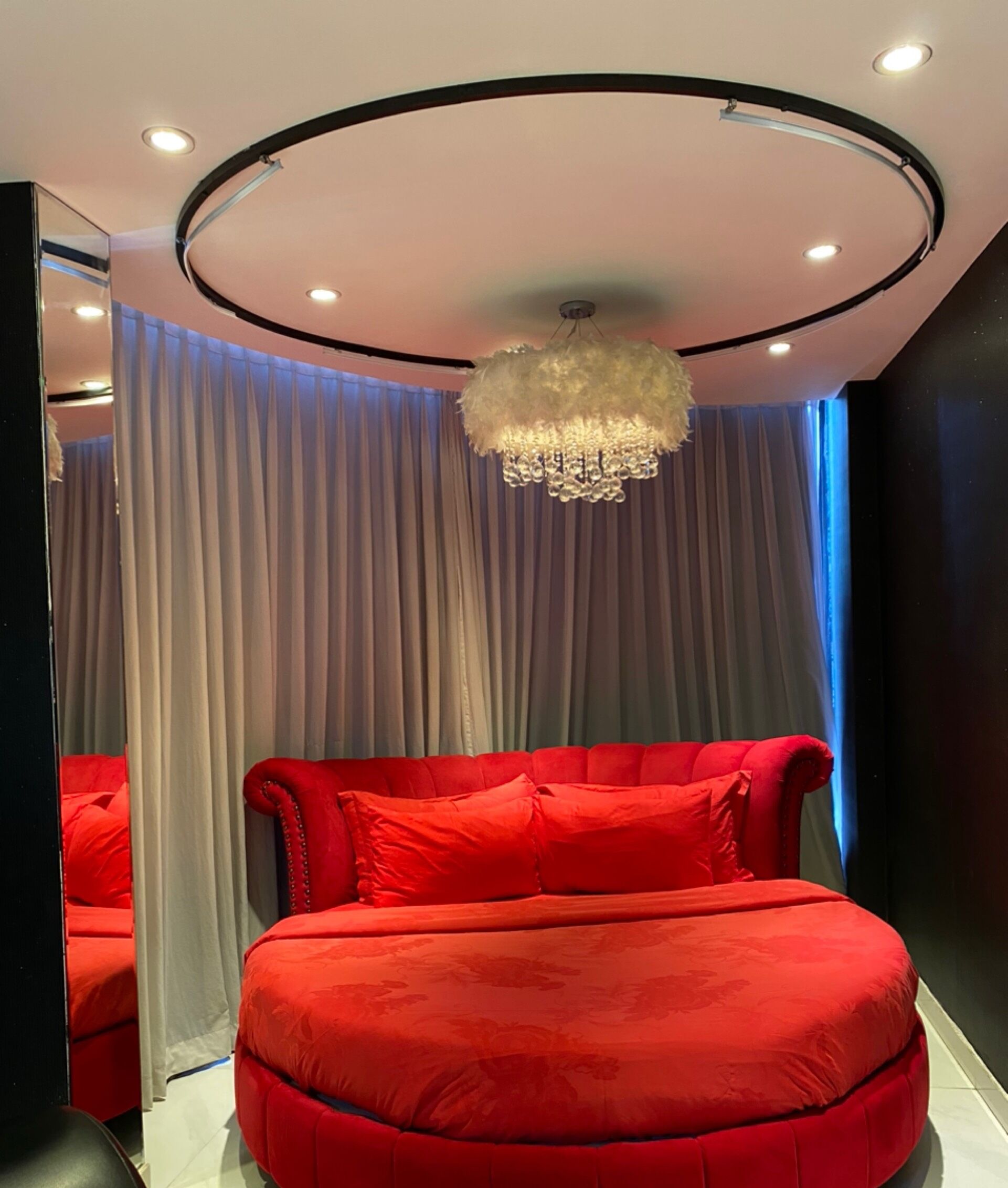A bedroom with a large bed, a mirror, and a chandelier.