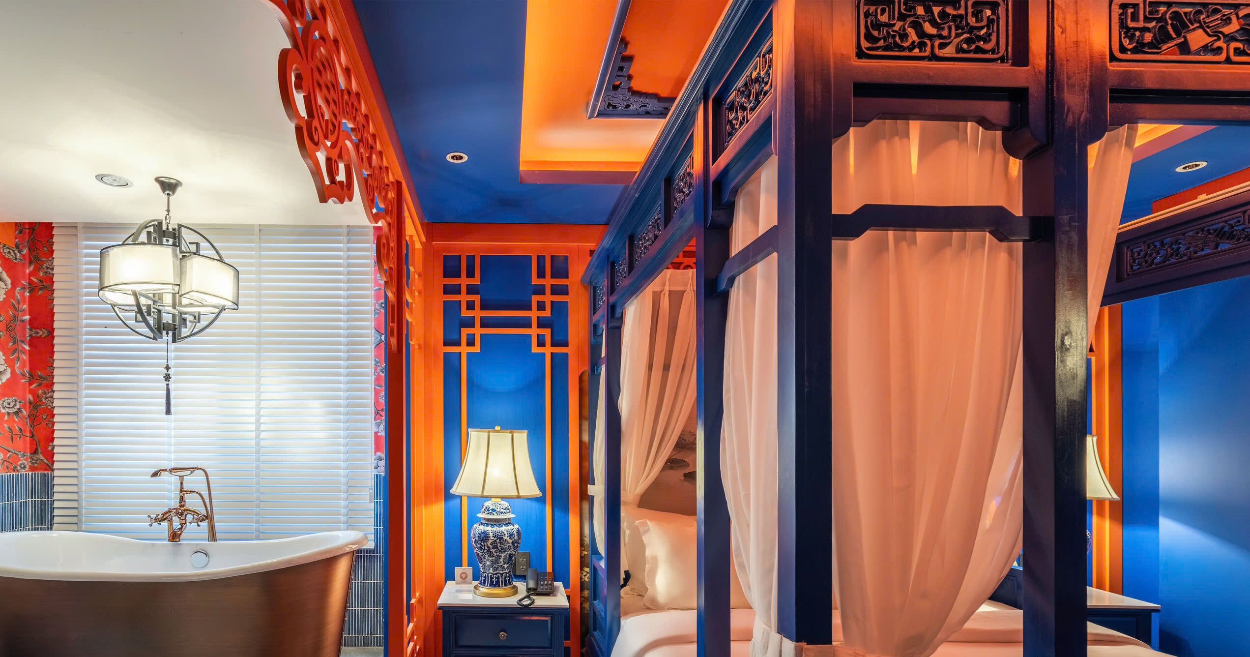 Una habitación con bañera, una mesita de noche con lámpara y una cama con dosel.