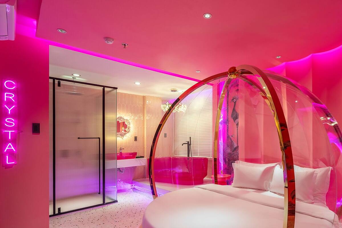 Ein Zimmer mit Baldachinbett, einer Duschkabine aus Glas und einem Neonlicht.