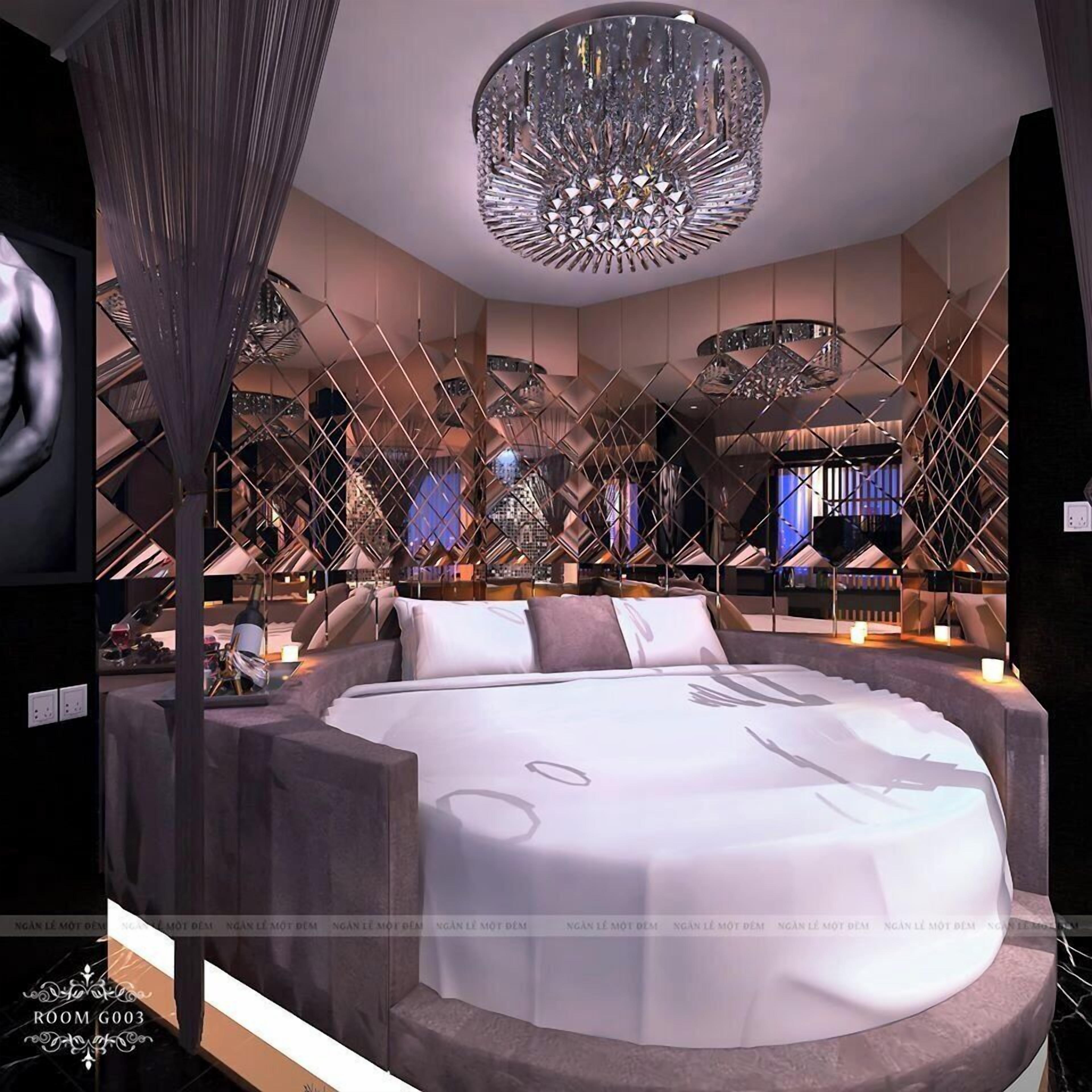 A modern bedroom with a large bed, a chandelier, and a unique geometric ceiling design.