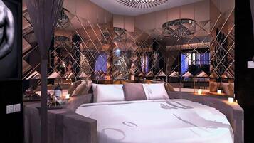 A modern bedroom with a large bed, a chandelier, and a unique geometric ceiling design.