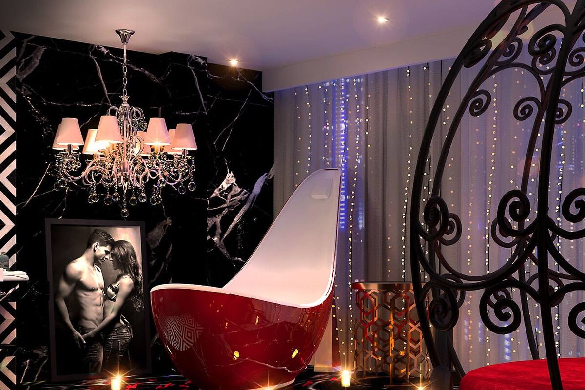 Ein modernes Schlafzimmer mit einer Lüster, einem roten Sessel und einer Wand mit Lichterkette.