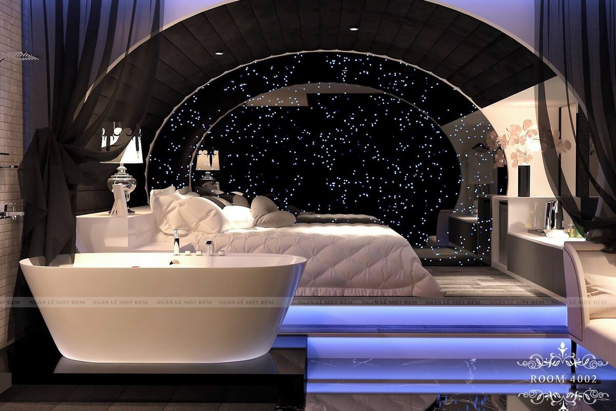 Ein luxuriöses Schlafzimmer mit einem großen Bett, einer Badewanne und Blick auf einen sternenübersäten Nachthimmel.