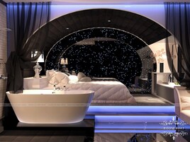 Quarto luxuoso com uma cama grande, uma banheira e vista para um céu estrelado.