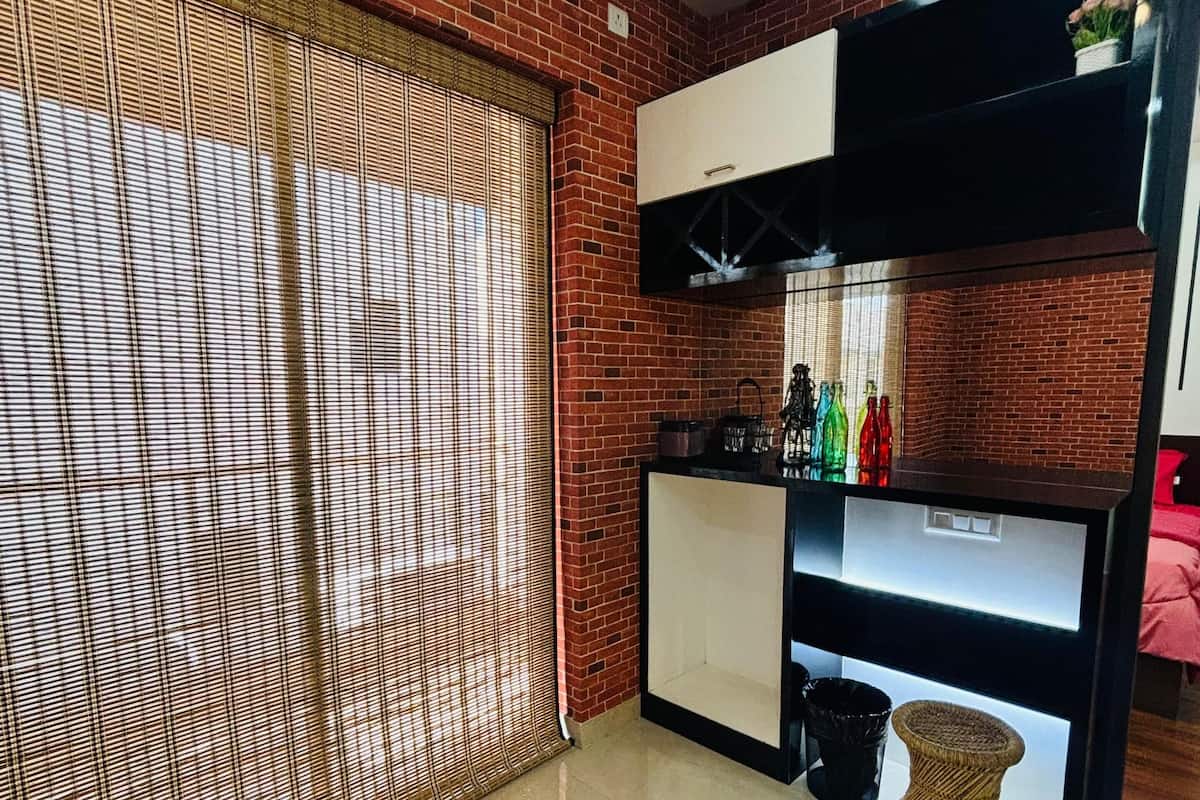 Una cocina moderna con pared de ladrillo, una ventana con persianas y encimera negra con varios objetos.