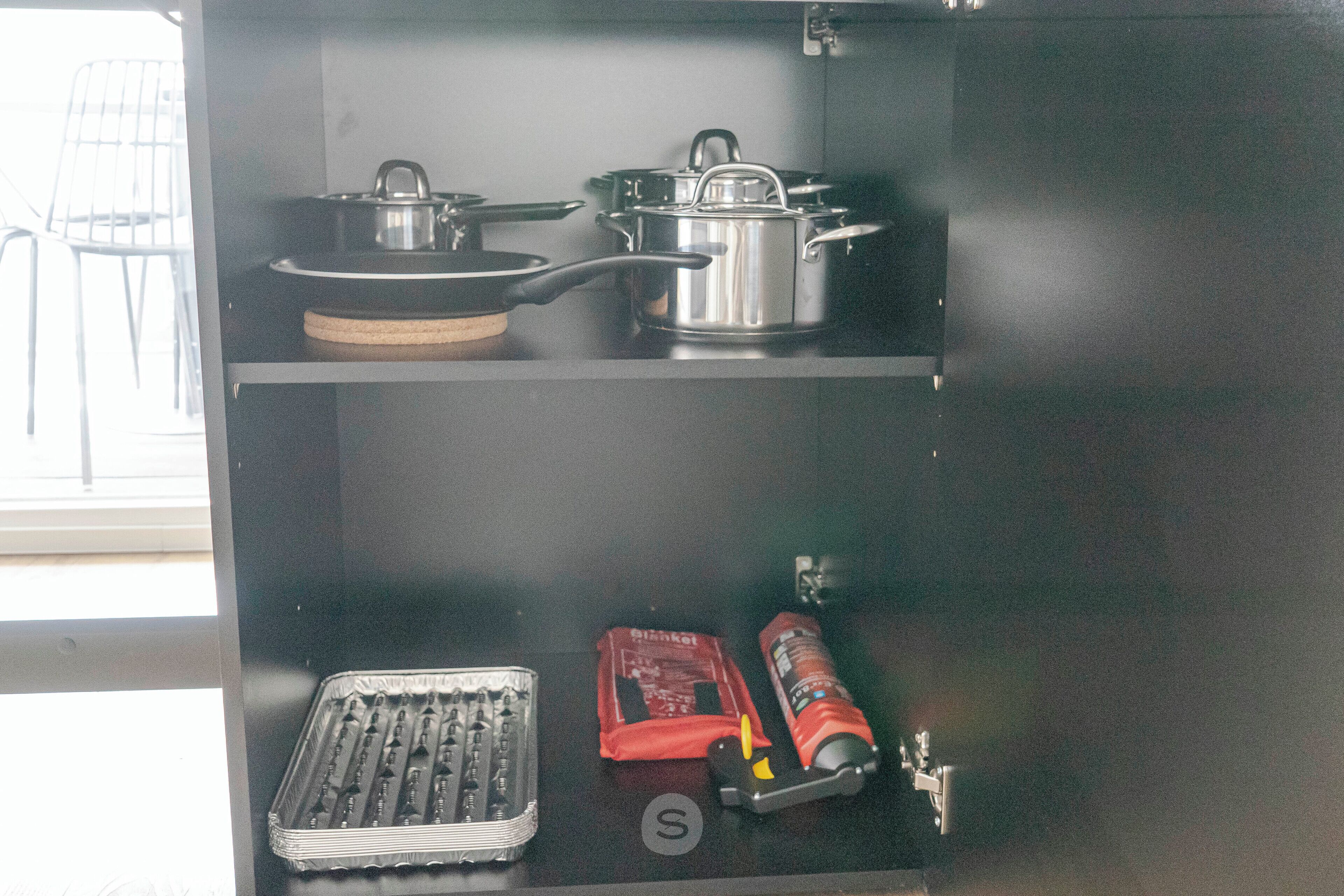 Una cocina con ollas y sartenes de acero inoxidable sobre una encimera negra.