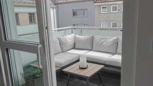 A balcony with a white sofa, a small table, and a potted plant. - Perfect city center location, 107 sqm, directly at the opera house in suite flair with balcony! (Nürnberg)