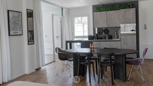 A modern kitchen with a dining area, featuring a large island, dark chairs, and a view of the city. - Perfect city center location, 107 sqm, directly at the opera house in suite flair with balcony! (Nürnberg)