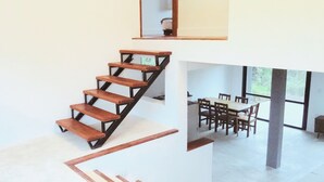 A modern interior with a wooden staircase, a dining area with a table and chairs, and large windows. - Modern House in Nature at Villa Monte Reserve (Palma Sola)