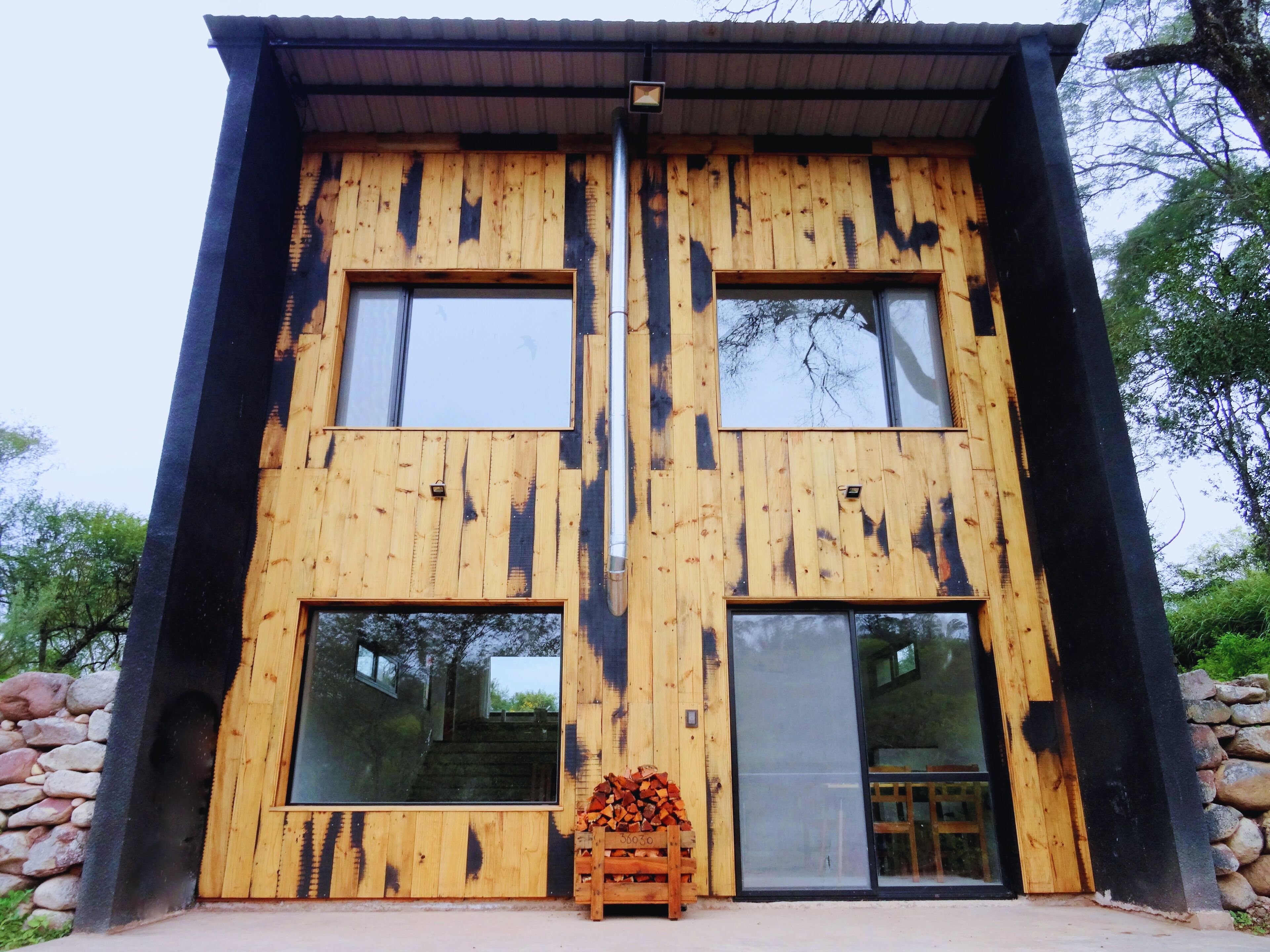 A modern wooden building with two large windows and a door.