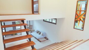 A modern interior with a wooden staircase, a sofa, and a colorful stained glass window. - Modern House in Nature at Villa Monte Reserve (Palma Sola)