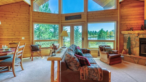 Un interior de cabaña acogedor con un ventanal grande, una chimenea y una zona de estar confortable.