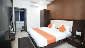 Een hotelkamer met een bed, een kledingkast, een bureau en een badkamer die door een geopende deur zichtbaar is.