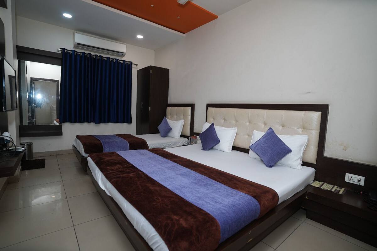 Habitación de hotel con dos camas, un espejo grande y un armario.