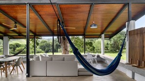 An outdoor living area with a hammock, a white sofa, and a dining table with chairs.