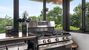 A modern kitchen with a stainless steel stove, a coffee maker, and a jar of Coca-Cola.