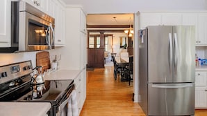A modern kitchen with stainless steel appliances, wooden flooring, and white cabinetry. - Charming Family Home Steps from UWSP & Downtown (Stevens Point)