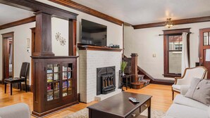 A living room with a fireplace, a television, and a bookshelf. - Charming Family Home Steps from UWSP & Downtown (Stevens Point)