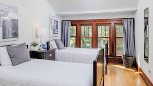 A bedroom with two beds, a nightstand, a lamp, a window with curtains, and a ceiling fan. - Charming Family Home Steps from UWSP & Downtown (Stevens Point)