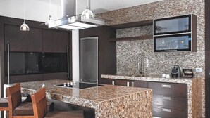 Una cocina moderna con encimeras de granito, electrodomésticos de acero inoxidable y un televisor empotrado.