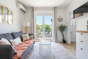 Een moderne woonkamer met een grijze bank, een ronde witte tafel en een balkon met uitzicht.